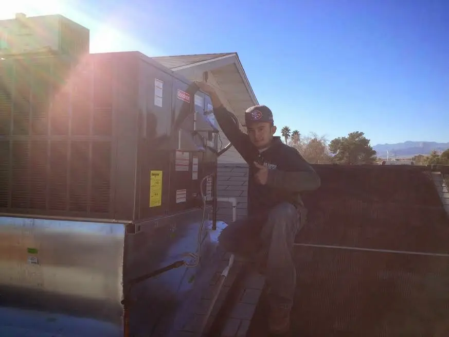 HVAC technician performing Air Duct Repair on a rooftop unit in Liberty
